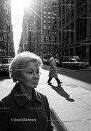 Elderly Woman Walking on City Street in Black and White Urban Scene