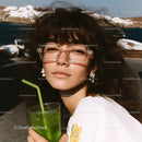 Fashionable Young Woman with Wavy Hair and Green Juice on Beach