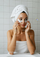 Young woman applying under eye patches in bathroom