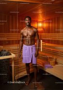 Fit Man Relaxing in Wooden Sauna with Towel Around Waist
