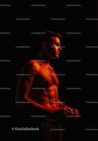 Contemplative shirtless man illuminated by warm light