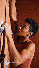 Focused woman climbing indoor rock wall with strength