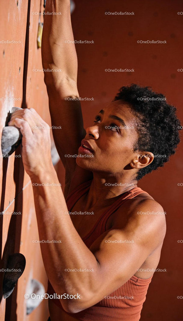 Focused woman climbing indoor rock wall with strength