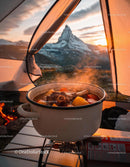 Hearty stew cooking inside tent with mountain sunset view