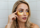 Young Woman Applying Gold Eye Patches for Rejuvenating Skin Treatment