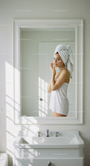 Woman in Towel Applying Cream in Minimalist Bathroom Mirror