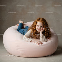 Smiling redhead girl relaxing on soft pink bean bag