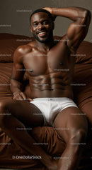 Smiling muscular man relaxing on bed in white briefs