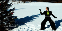 Woman in bold black suit posing in snowy landscape
