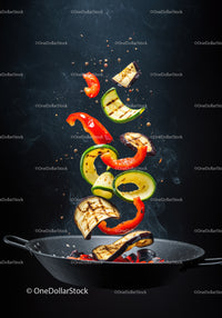Grilled vegetables tossed midair in black frying pan