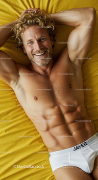 Smiling man relaxing on yellow bed in white briefs