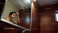 Young man carefully combing hair in steamy bathroom mirror