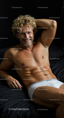 Smiling muscular man relaxing on bed in white underwear