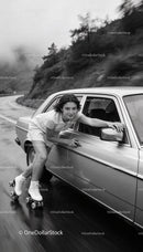 Young Woman Roller Skating Alongside Car on Curvy Road