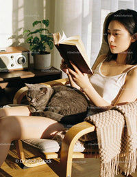 Calm woman reading book with cat in sunny living room
