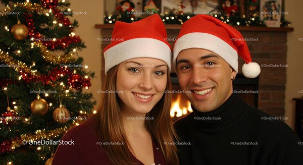 Smiling couple wearing Santa hats by Christmas tree