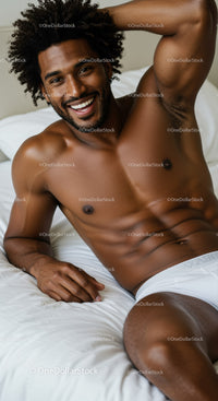 Smiling man relaxing shirtless on bed in casual pose