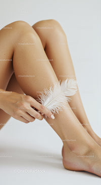 Elegant Close-Up of Female Legs with White Feather on Smooth Skin