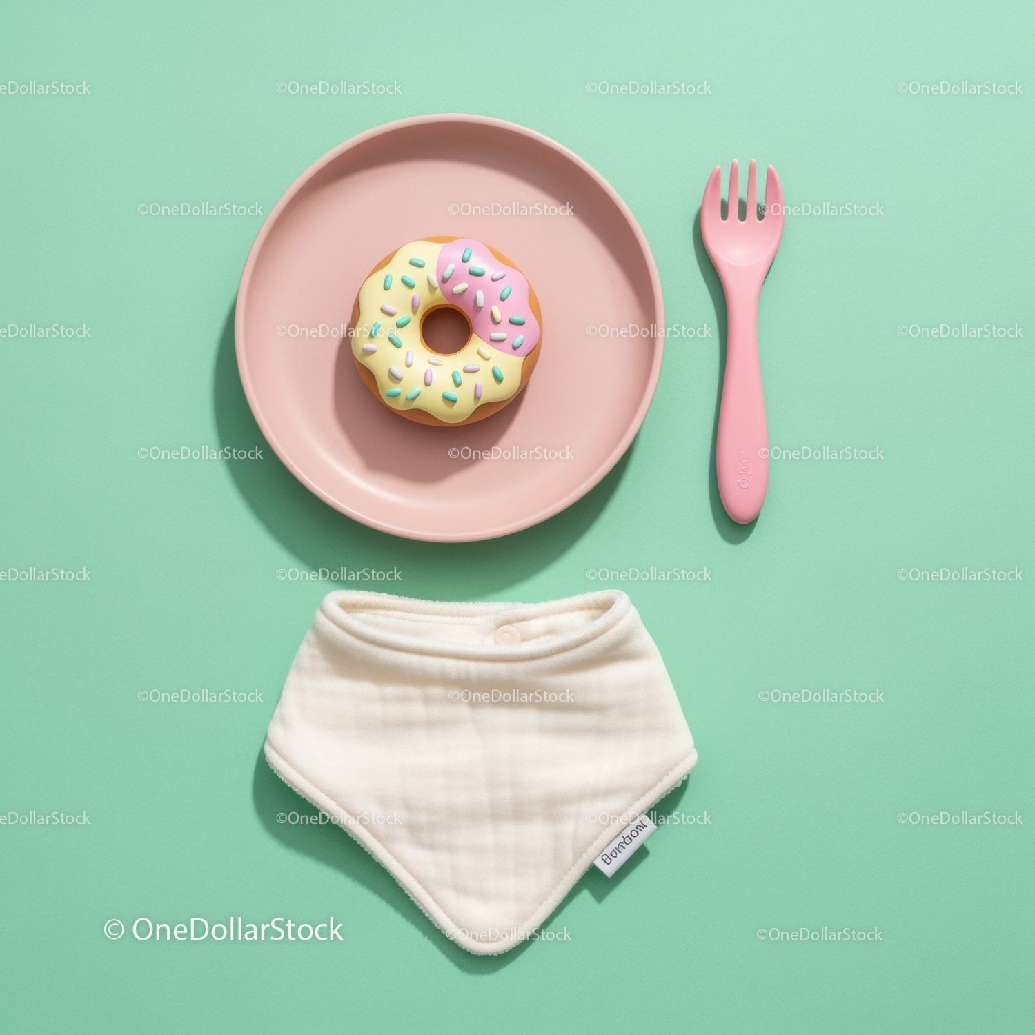 Colorful donut on pastel plate with baby bib and fork