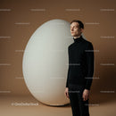 Calm man standing near oversized textured egg sculpture
