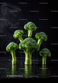 Fresh broccoli florets rising with steam on black surface