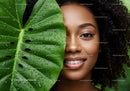 Smiling Woman with Curly Hair and Green Tropical Leaf in Lush Nature