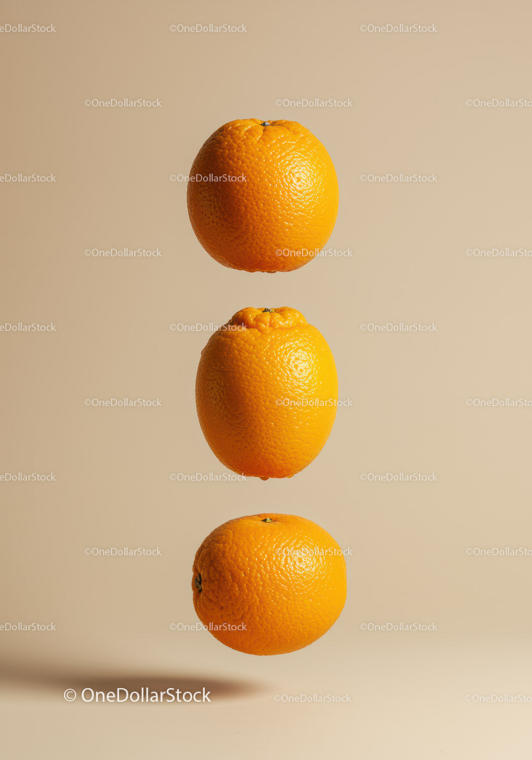 Three Fresh Oranges Suspended on Soft Beige Background