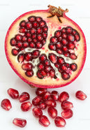 Fresh pomegranate half with scattered seeds on white background
