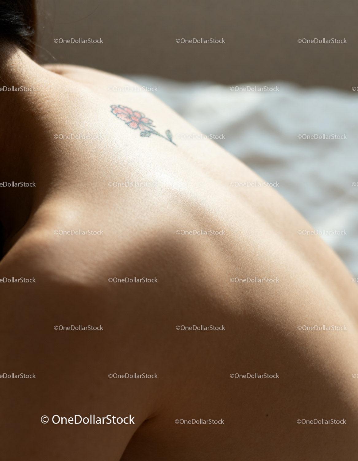 Close-up of bare back with small flower tattoo