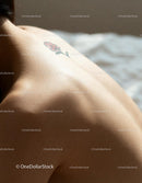 Close-up of bare back with small flower tattoo