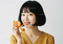 Young Woman with Fresh Orange and Bright Smile in Studio