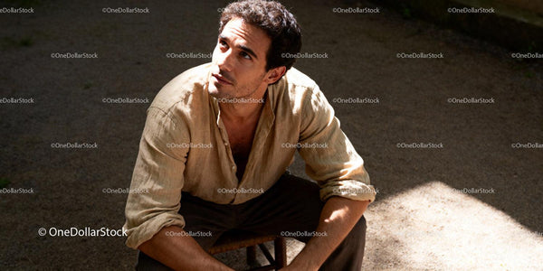 Thoughtful young man sitting in warm sunlight outdoors