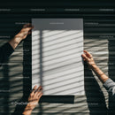 Hands holding blank paper with shadows on wooden wall