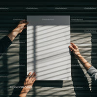 Hands holding blank paper with shadows on wooden wall