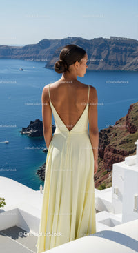 Woman in pale yellow dress overlooking blue sea cliffs