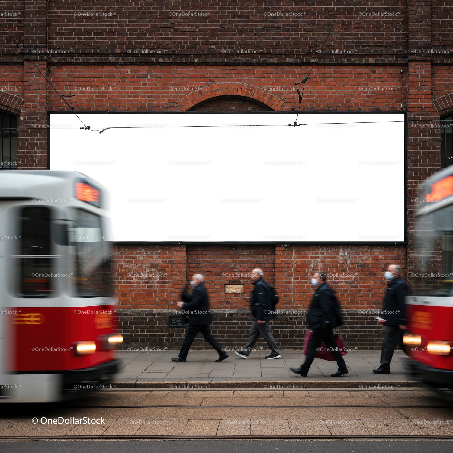 Commuters walking by brick wall with blank billboard