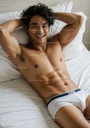 Smiling young man relaxing on bed wearing white underwear