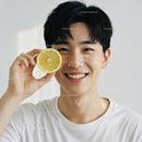 Smiling Young Man with Lemon Slice in Bright Studio Portrait