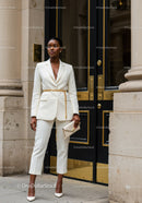 Confident woman in elegant white suit standing outside building
