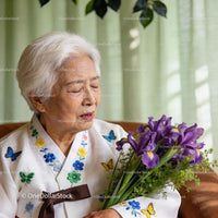 Elderly woman in traditional dress holding irises with tears