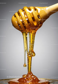 Close up of honey dripping from wooden dipper