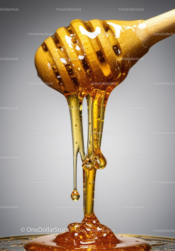 Close up of honey dripping from wooden dipper