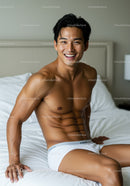 Smiling fit man sitting on bed in white underwear