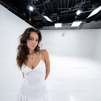 Young Woman in White Dress Standing in Modern Studio