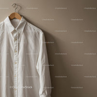 Classic white shirt hanging on wooden hanger indoors
