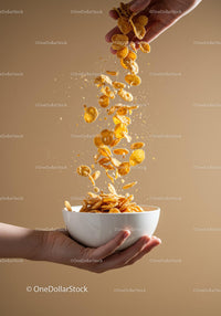 Hand Pouring Crunchy Cornflakes Into White Bowl