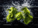 Green Bell Peppers Splashing into Water in Close-Up
