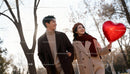 Happy young couple walking with heart balloon outdoors