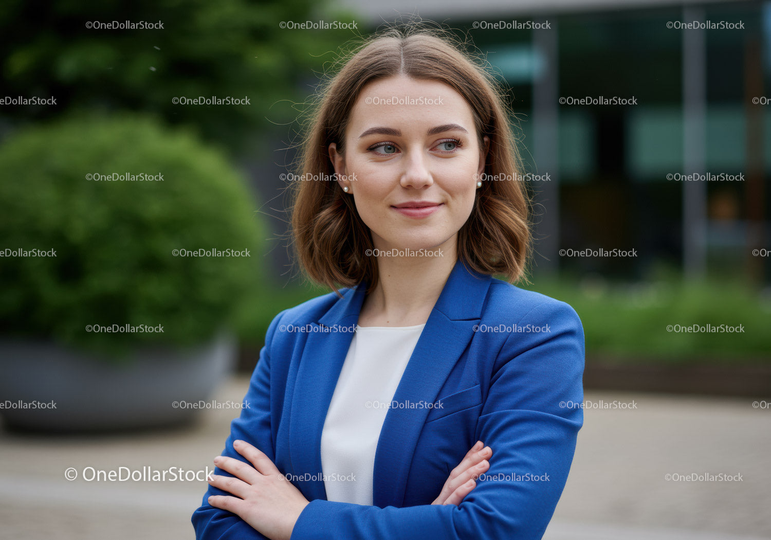 Pewna siebie kobieta w niebieskiej marynarce krzyżująca ramiona na zewnątrz wśród zieleni