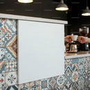 Barista handing coffee cup over colorful tiled counter